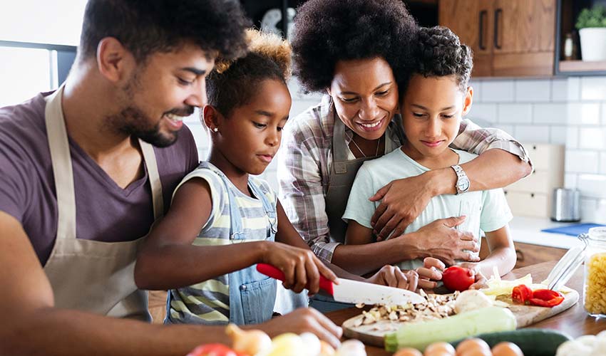 Family of four making a meal together in their kitchen.