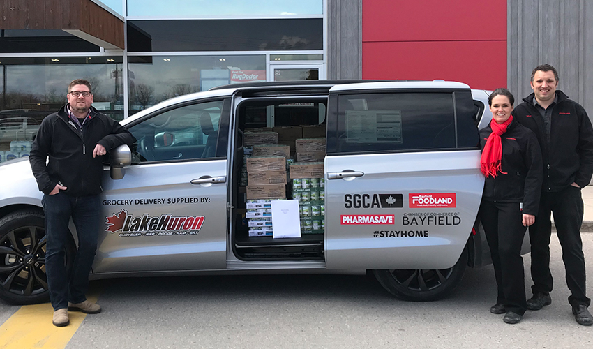 Foodland employees standing beside a grocery delivery van filled with groceries.