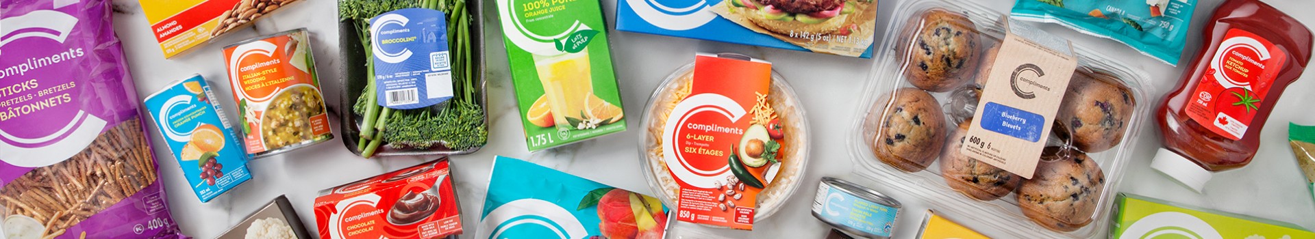 Two plates of grilled salmon with quinoa and orange slices on a white table with blue glasses, utensils, and a pan of more food in the background.