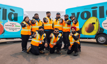 In this image, a group of Sobeys and Safeway employees is taking their picture in front of a Voila van.